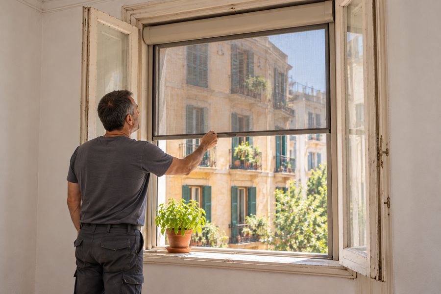 Mosquitera enrollable recién montada en una ventana de una finca antigua de Barcelona